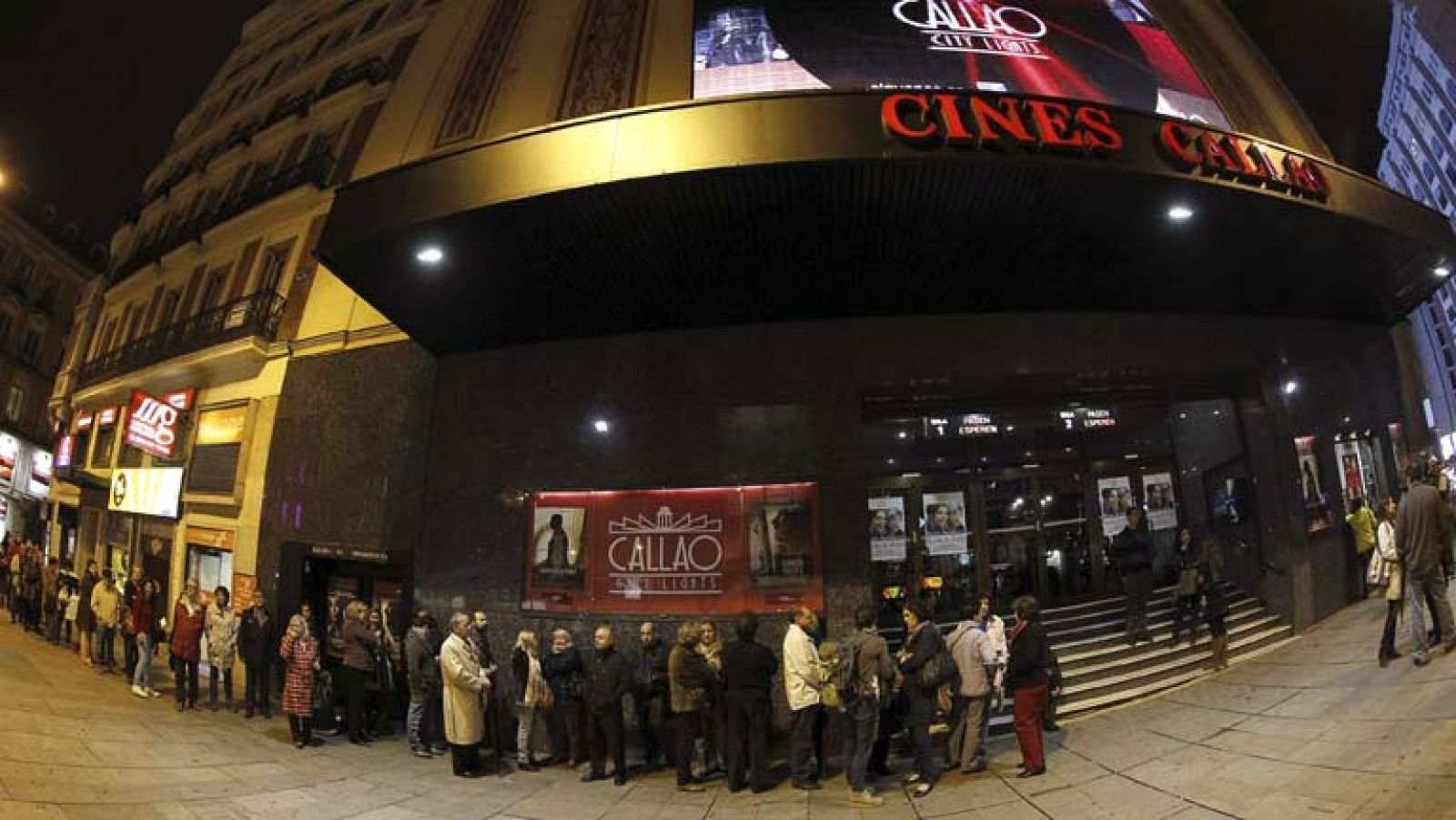Varias personas hacen cola a las puertas de los cines Callao, en Madrid