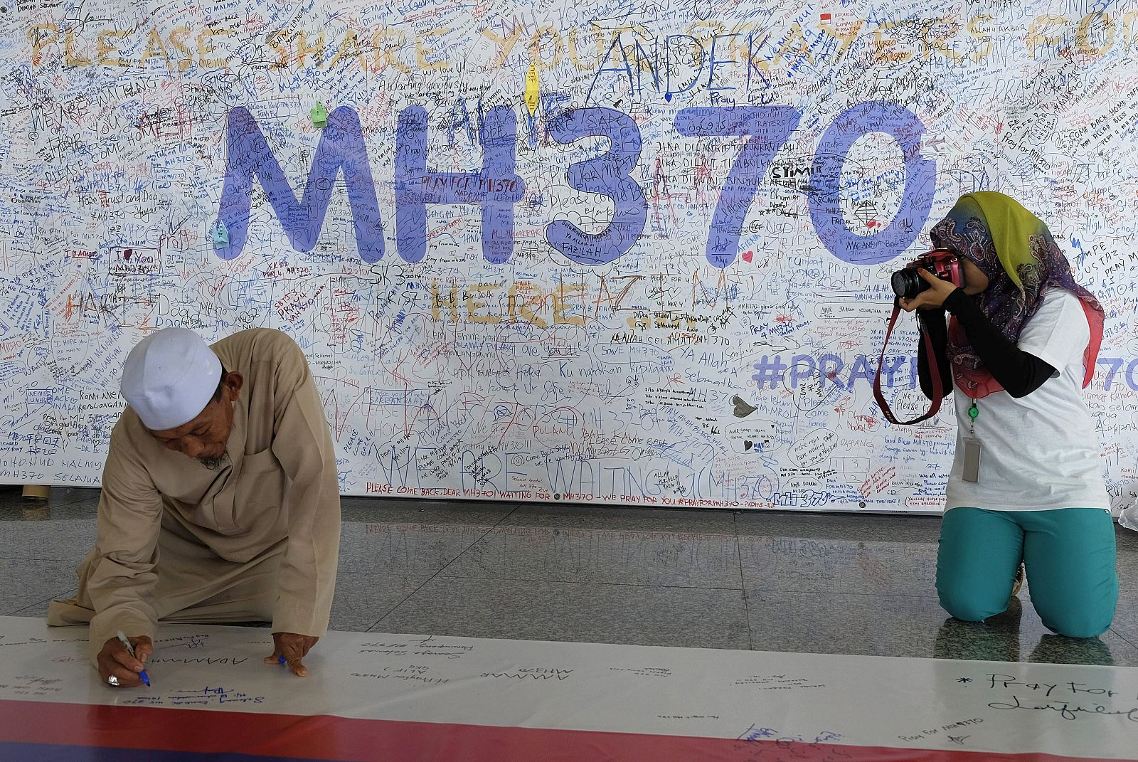 Un hombre escribe en una pancarta en recuerdo de los pasajeros del avión desaparecido en Malasia.