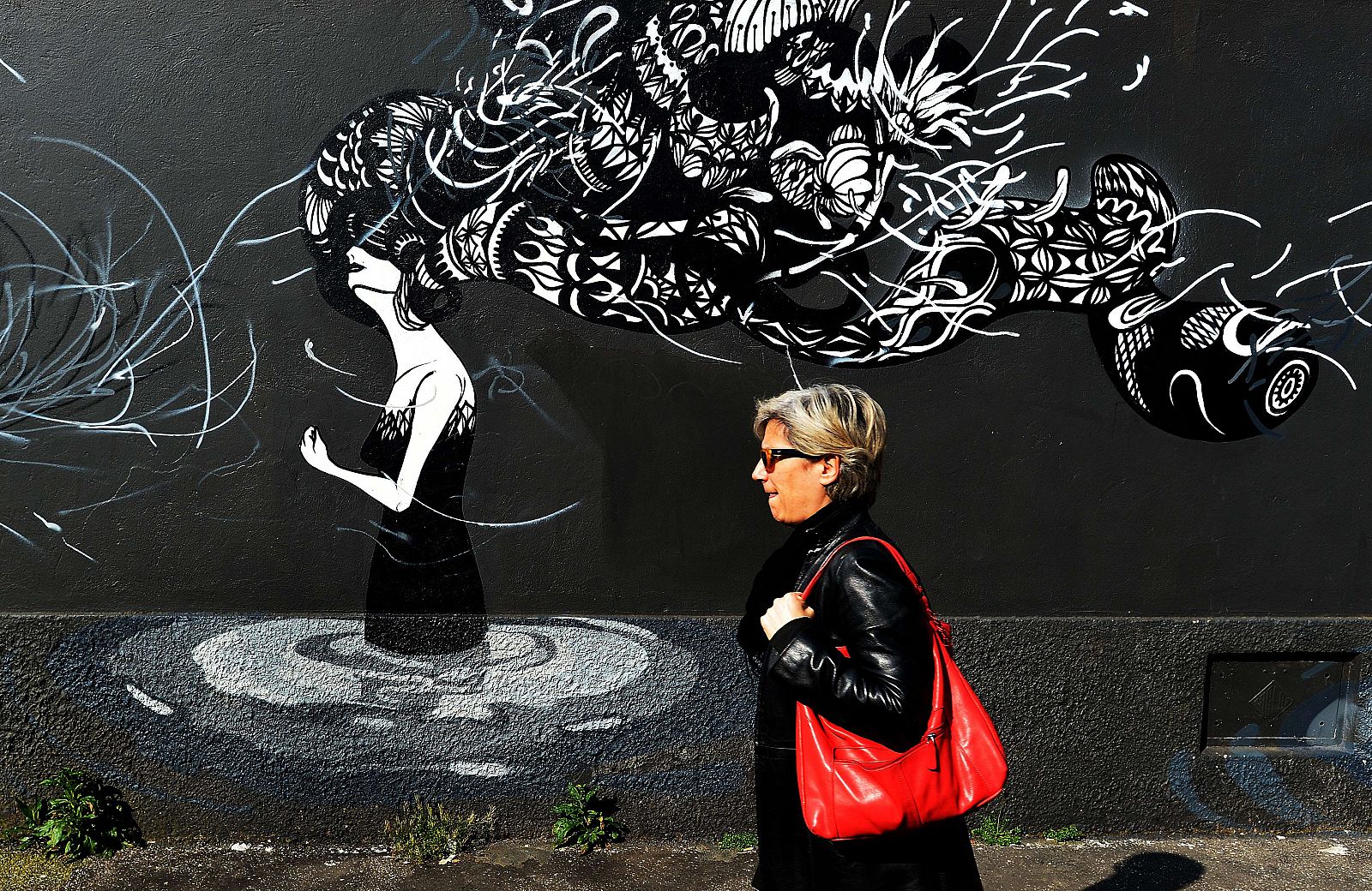 Una mujer pasa por delante de un graffiti