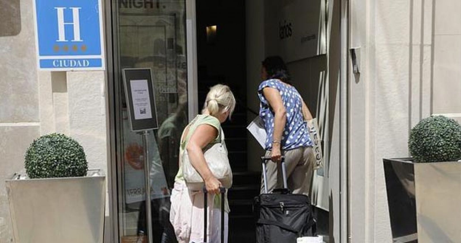 Dos turistas se asoman a la entrada de un hotel
