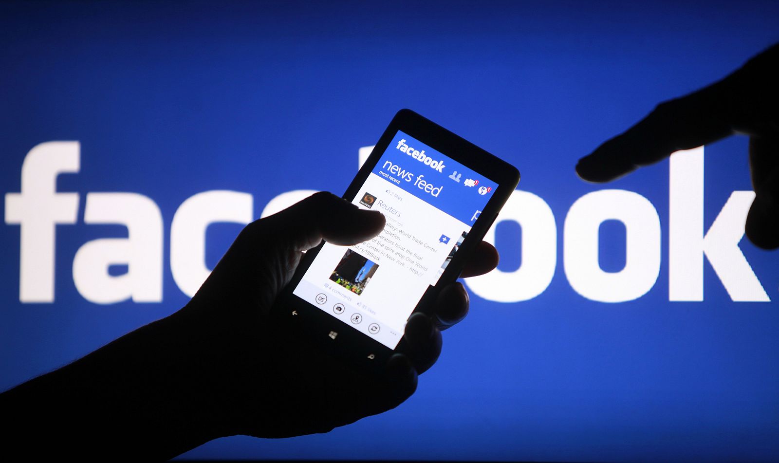 Imagen de un teléfono móvil con la aplicación de Facebook abierta delante de un anuncio de la compañia.