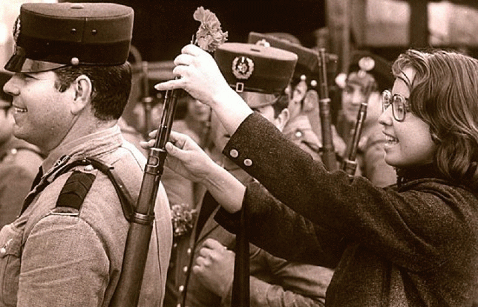 Una chica pone un clavel en el fusil de un militar durante la Revolución de los Claveles.