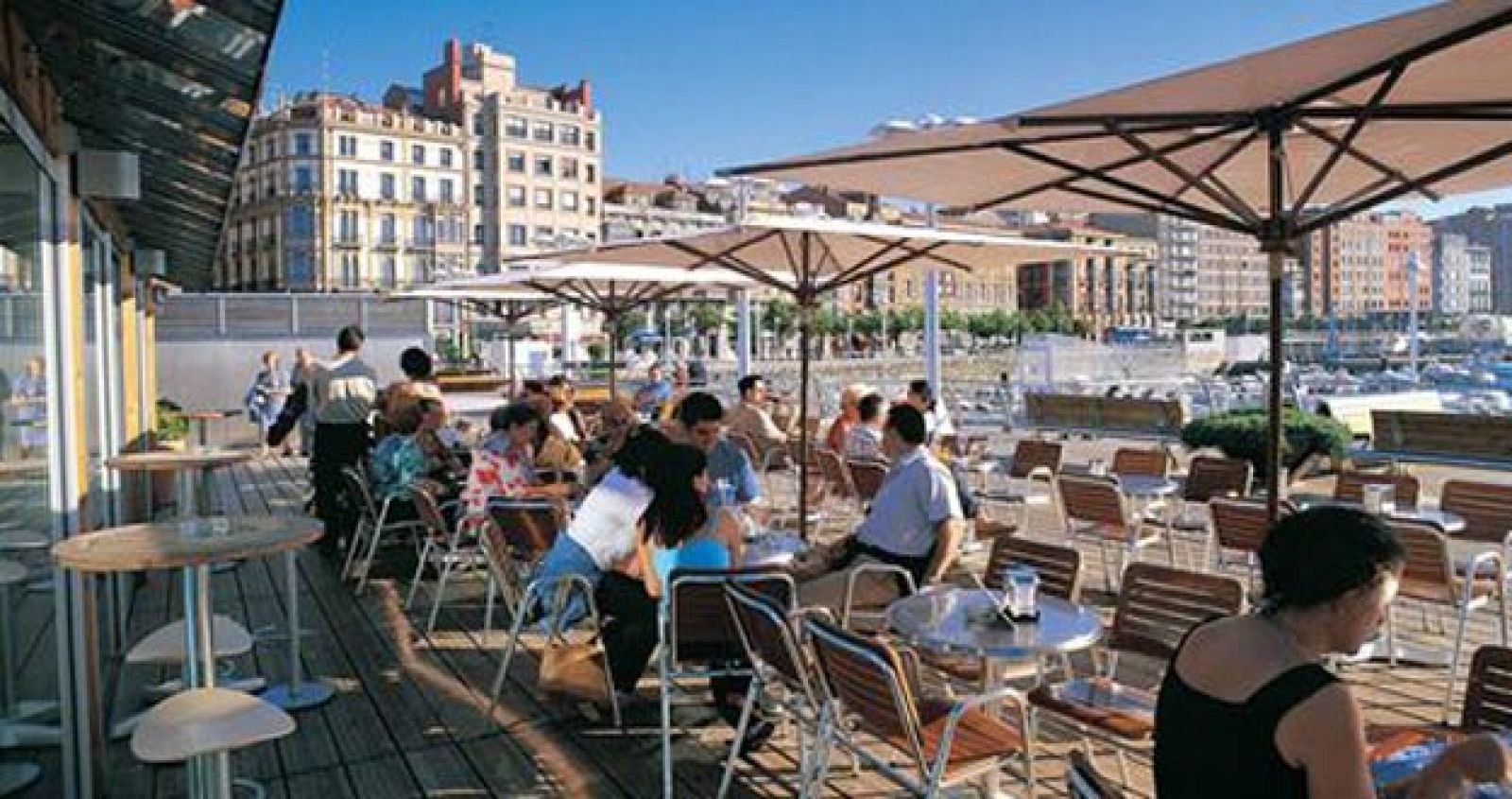 Turistas en una terraza junto a un puerto