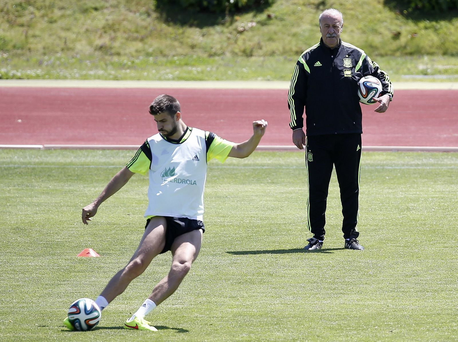 Spanish national soccer coach del Bosque looks on as Pique kicks the ball during a training session of the national soccer team at Las Rozas playground near Madrid