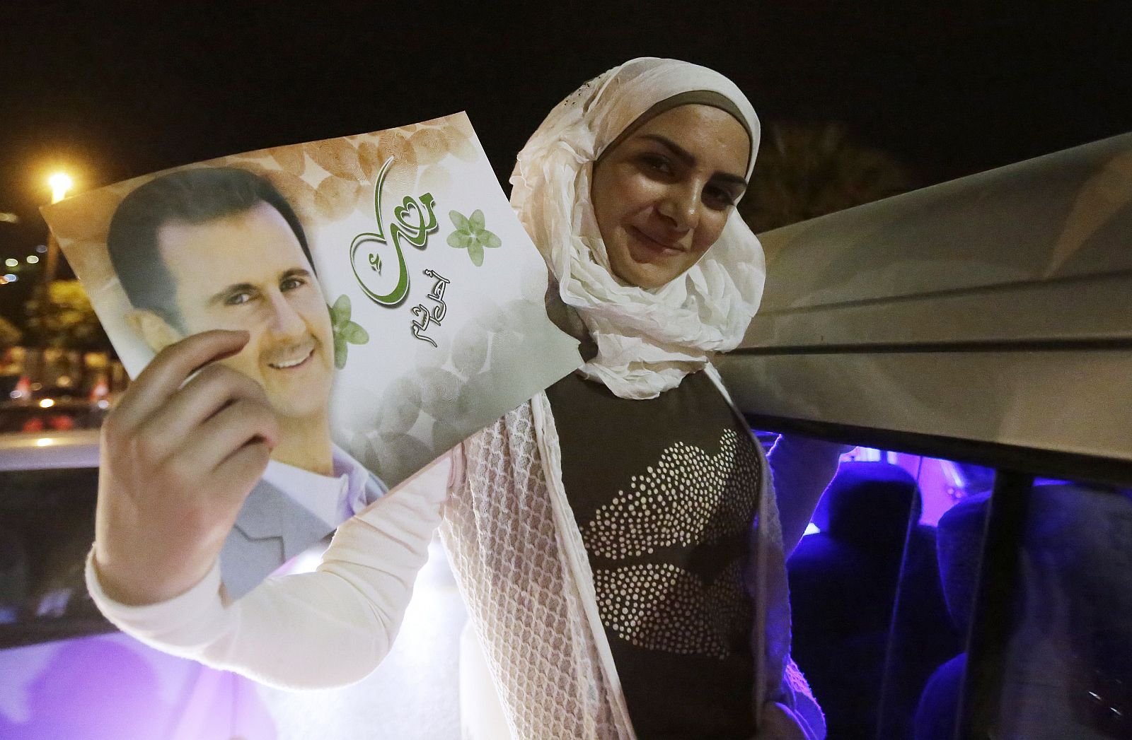 Una mujer sostiene un cuadro de Al Assad que muestra orgullosa al celebrar la victoria del político.