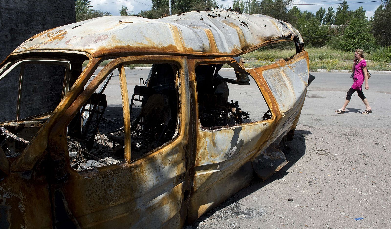 Una mujer pasea por delante de una furgoneta quemada en la ciudad ucraniana de Slavyansk