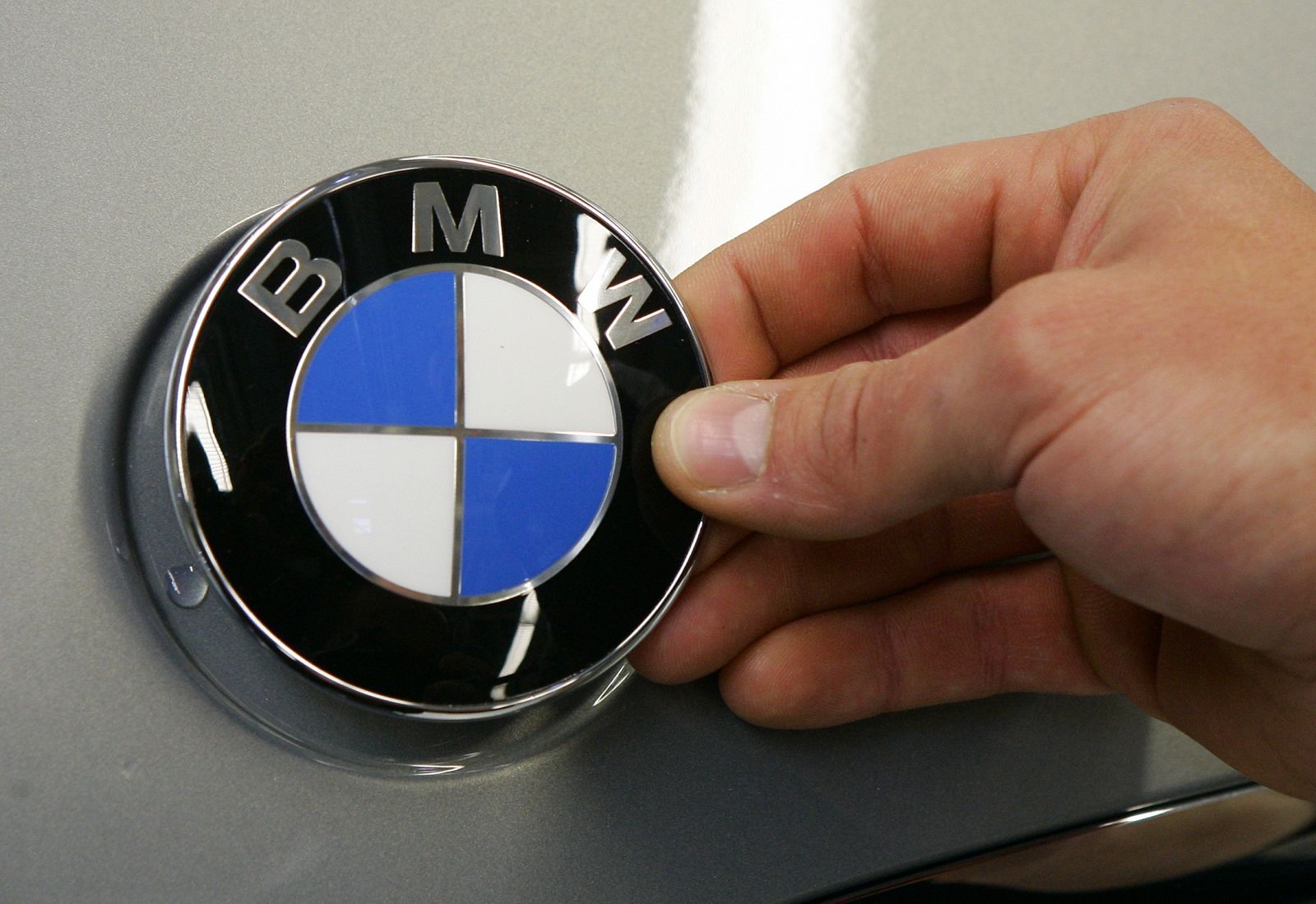 Un trabajador coloca el logo de BMW a un nuevo Serie 3 en la planta de Leipzig, Alemania