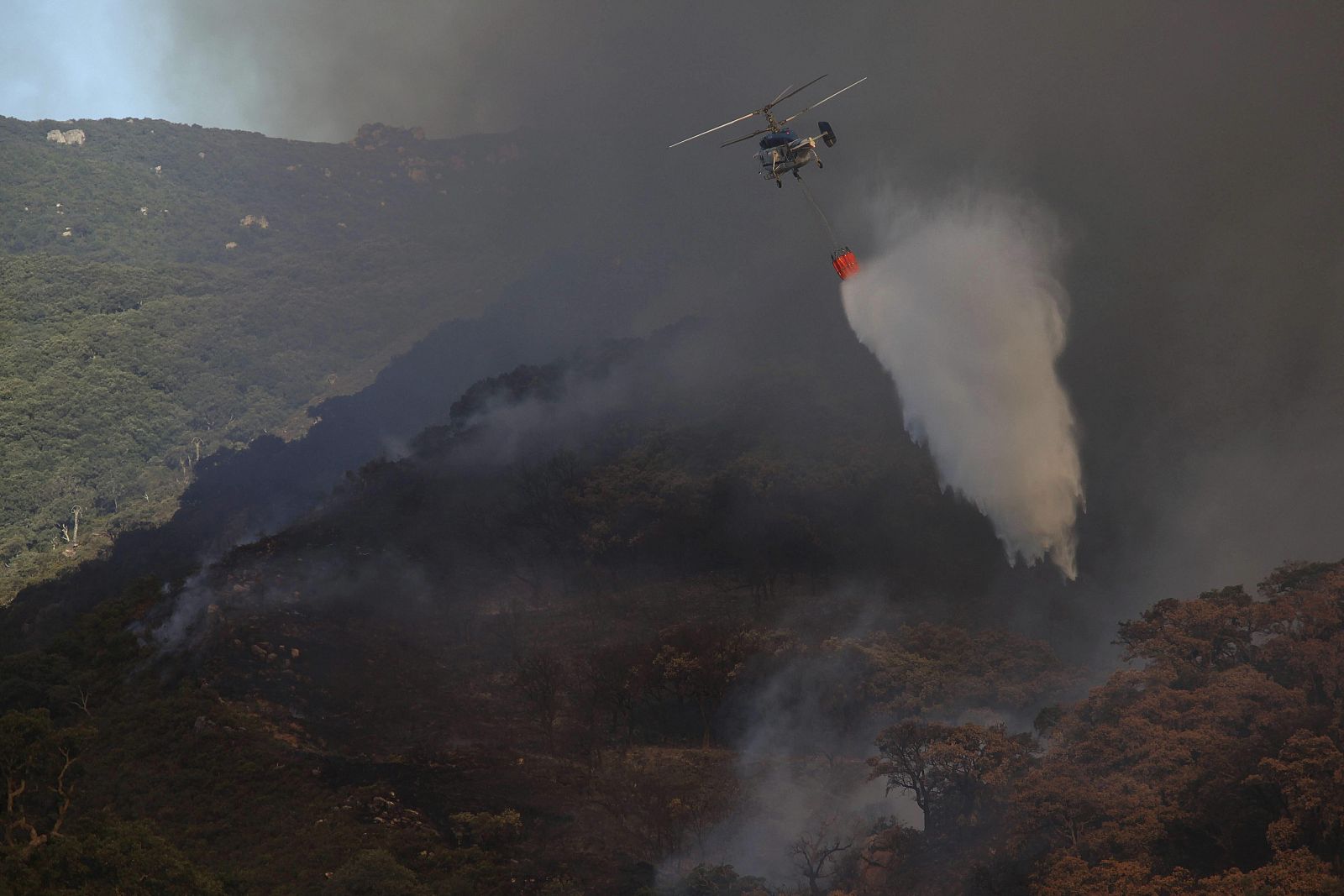 Un helicoptero trabajando en la extinción del incendio en el paraje del Río de la Miel, en Algeciras (Cádiz).