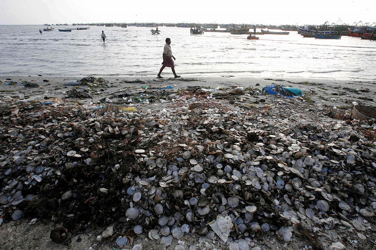 Un pescador camina entre la basura amontonada en la orilla en laciudad meridional india de Rameswaram.