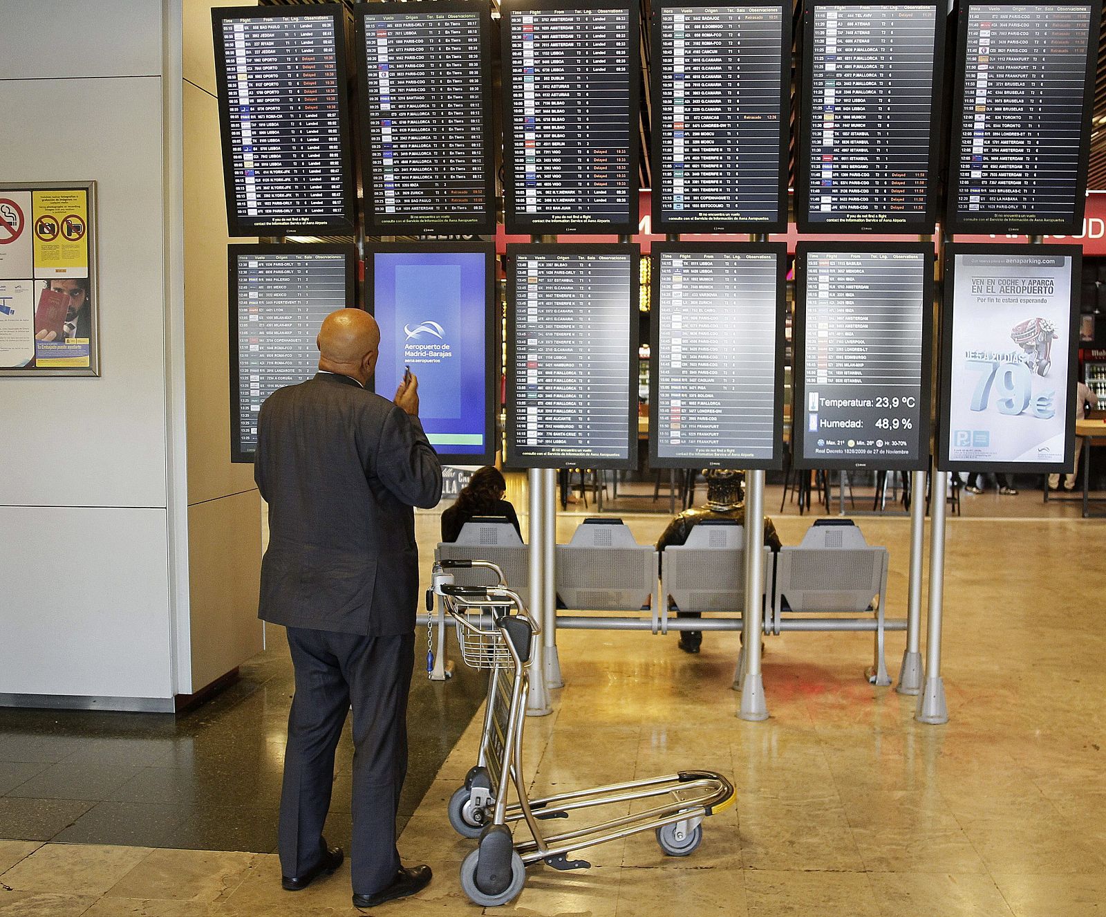 Un viajero consulta los horarios de los vuelos en paneles informativos del aeropuerto de Barajas