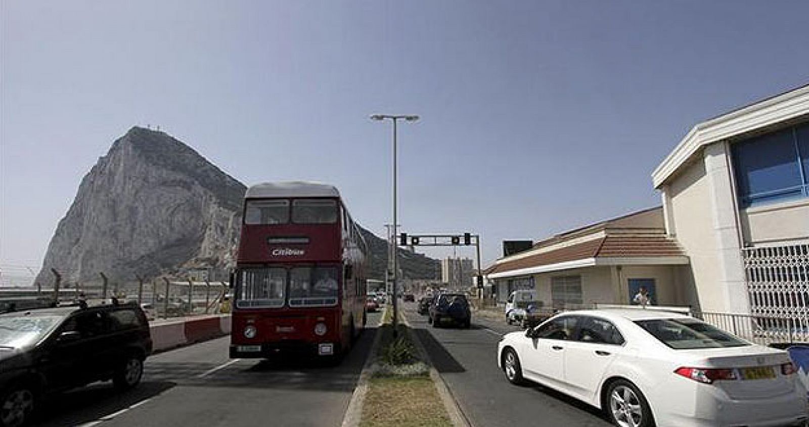 Vehículos circulando con el peñón de Gibraltar al fondo.