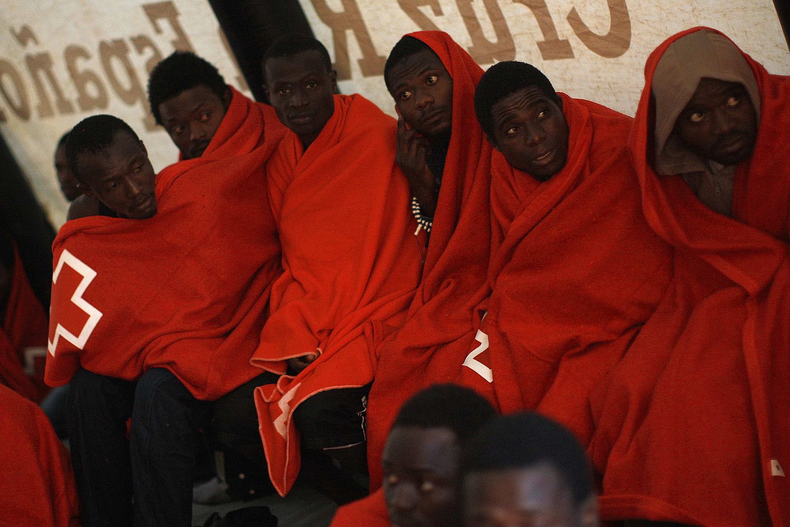 African immigrants wrapped in blankets take a rest inside a Red Cross tent after arriving on a rescue ship at the southern Spanish port of Tarifa