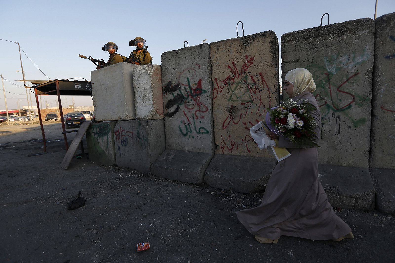 Una mujer palestina pasa ante un puesto de soldados israelíes en una protesta por la ofensiva sobre Gaza.