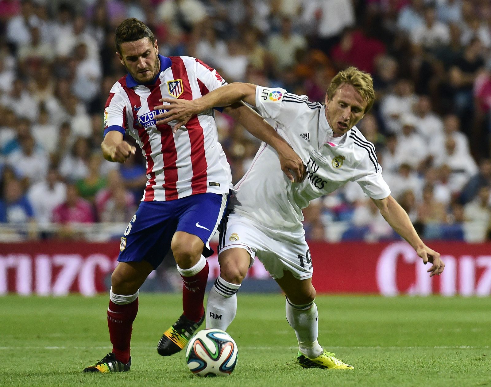 El futbolista croata Luka Modric (d) disputando un balón con Koke (i) en el partido de ida de la Supercopa de España disputado en el Santiago Bernabéu.