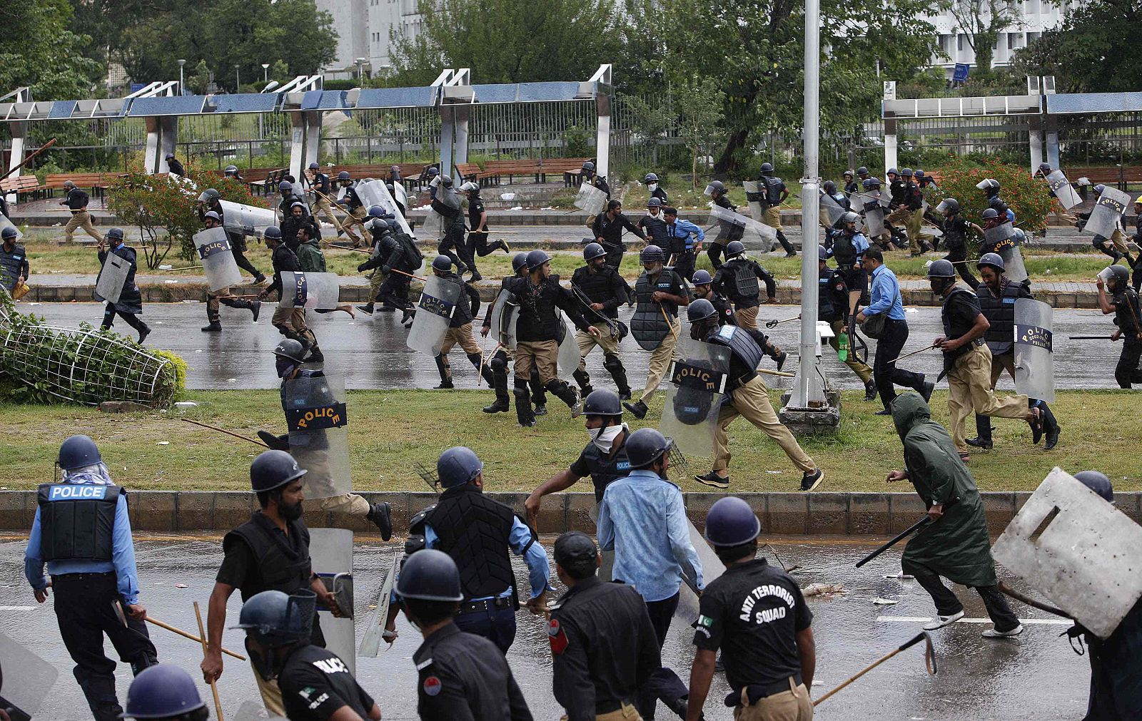 Policías paquistaníes se repliegan ante el avance de manifestantes hacia la residencia del primer ministro, este lunes  en Islamabad.