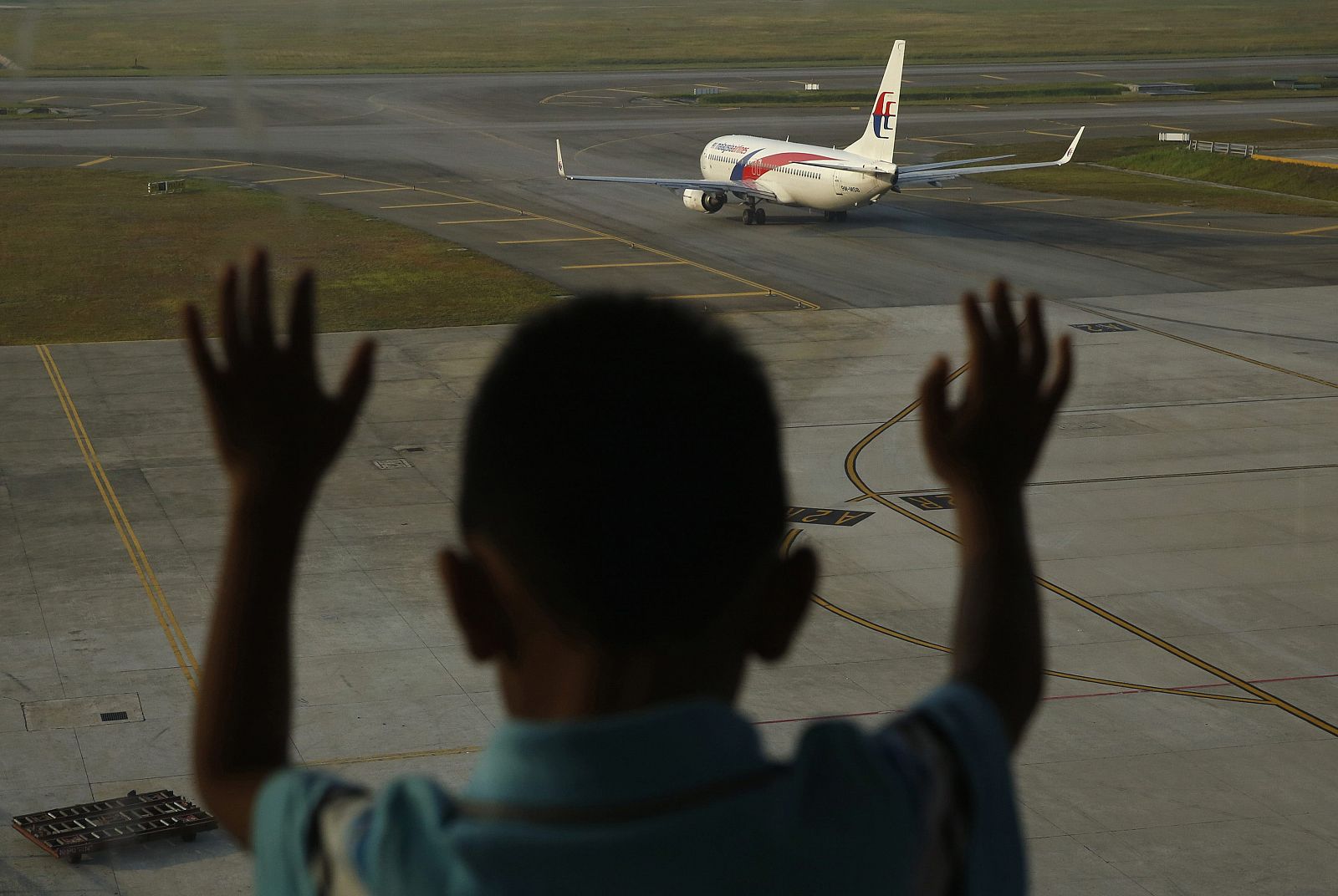Un niño observa un avión de Malaysia Airlines en el aeropuerto de Kuala Lumpur