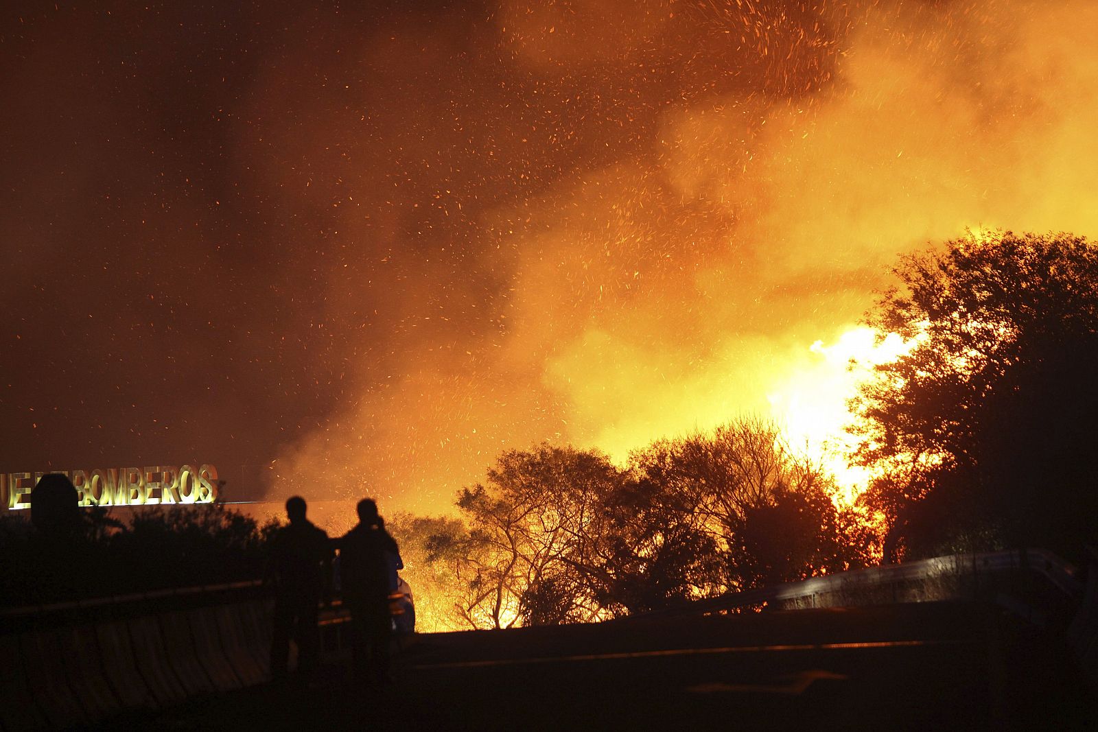 Dos policías cortan un puente amenazado por las llamas en un incendio forestal en Cádiz, el pasado 28 de agosto.