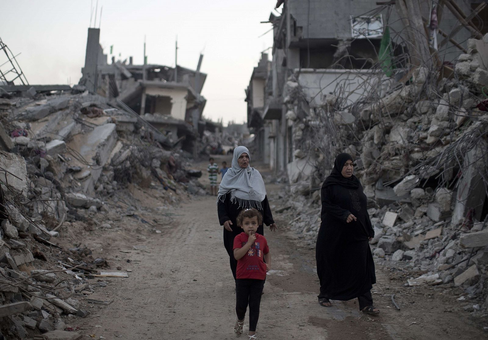 Mujeres palestinas caminan en medio de edificios de Gaza que fueron destruidos durante los 50 días de conflicto entre Israel y Hamas