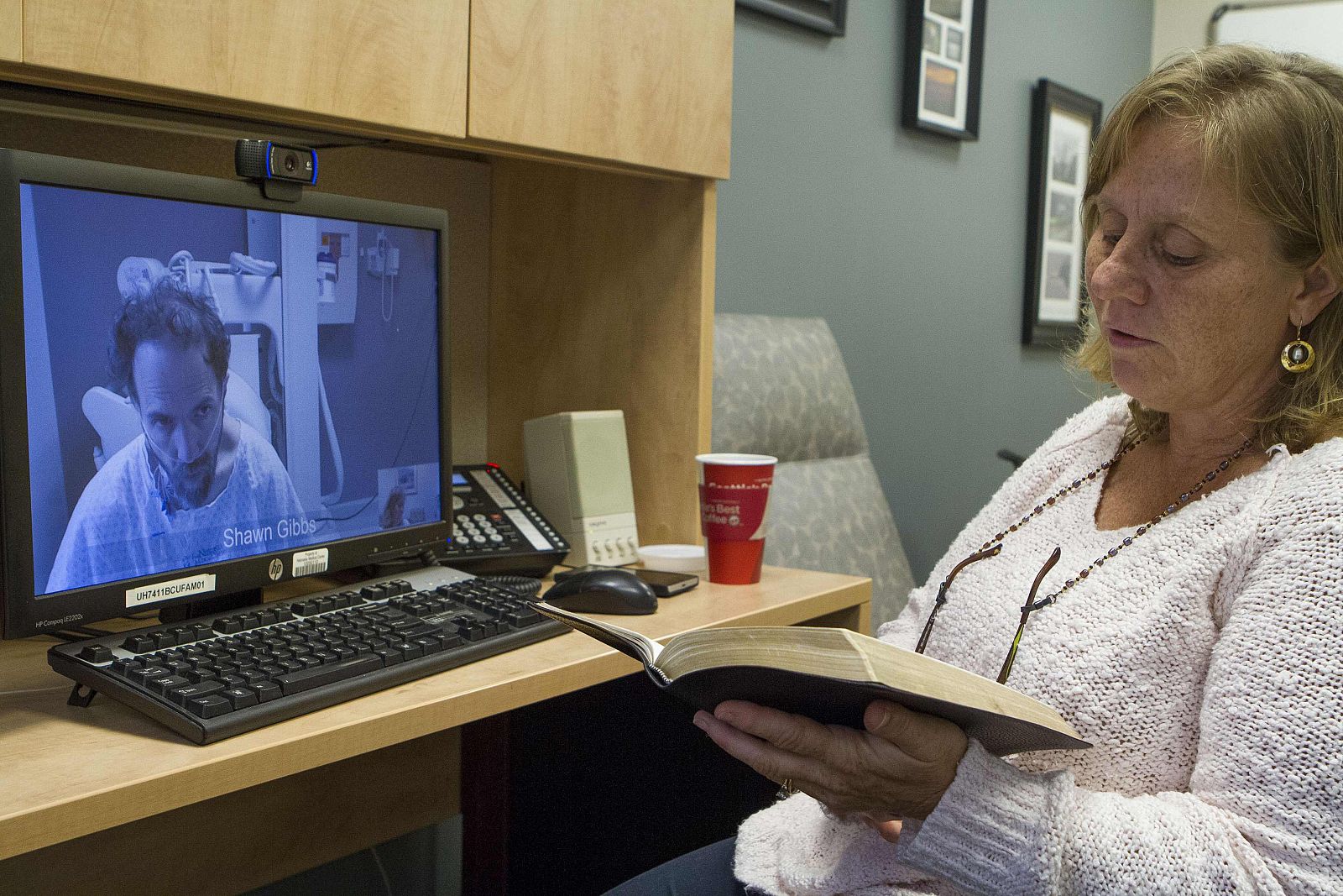 Handout shows Debbie Sacra, wife of Dr. Rick Sacra, reading Bible verses to him during a video conference at the Nebraska Medical Center in Omaha, Nebraska