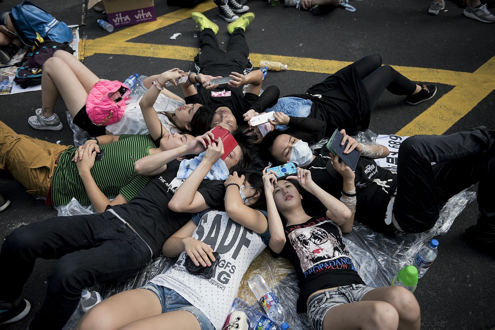 Un grupo de jóvenes manifestantes usan sus móviles en medio de la protesta en la principal arteria de Hong Kong.