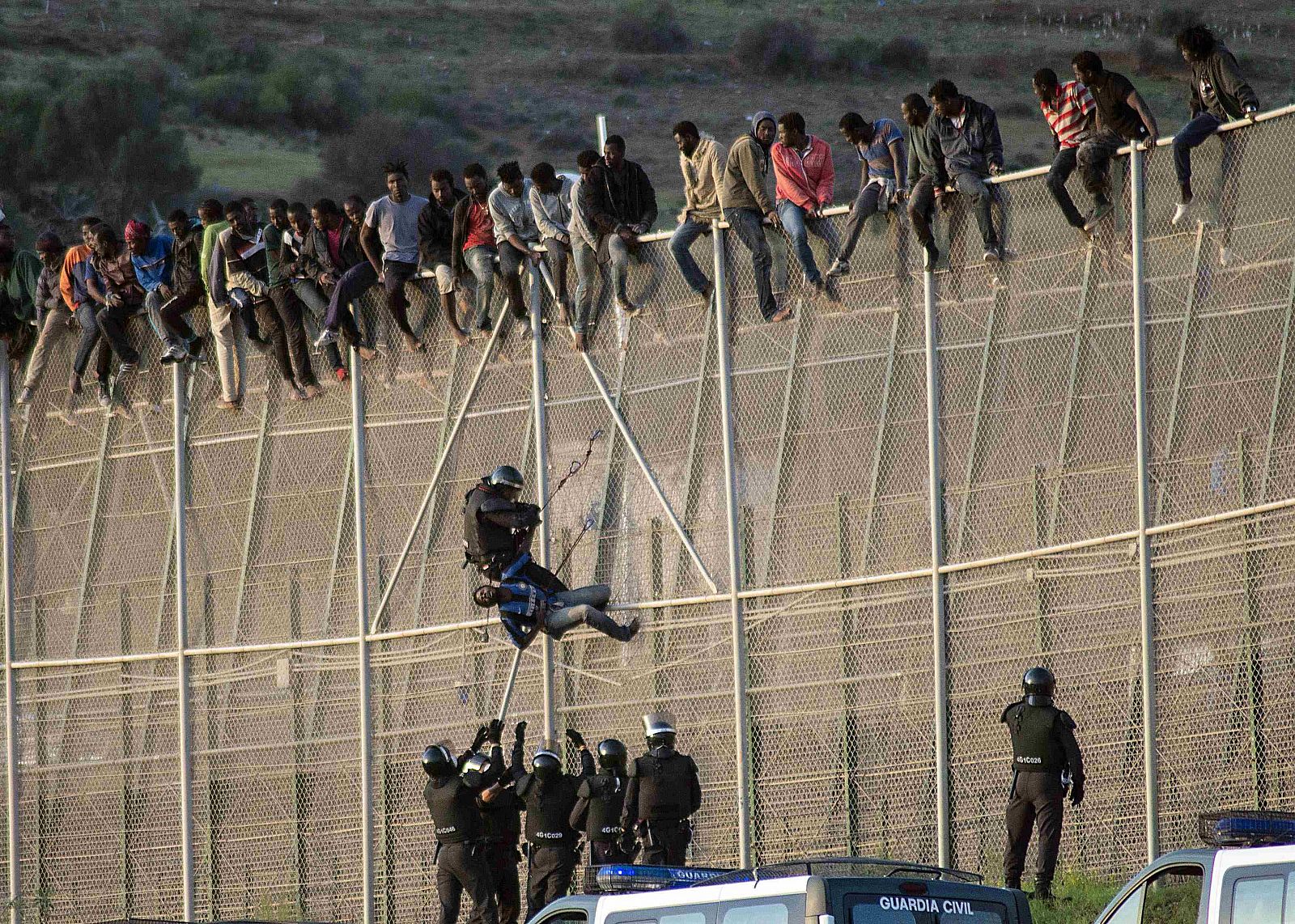 Un agente de la Guardia Civil detiene en la valla de Melilla a un inmigrante subsahariano