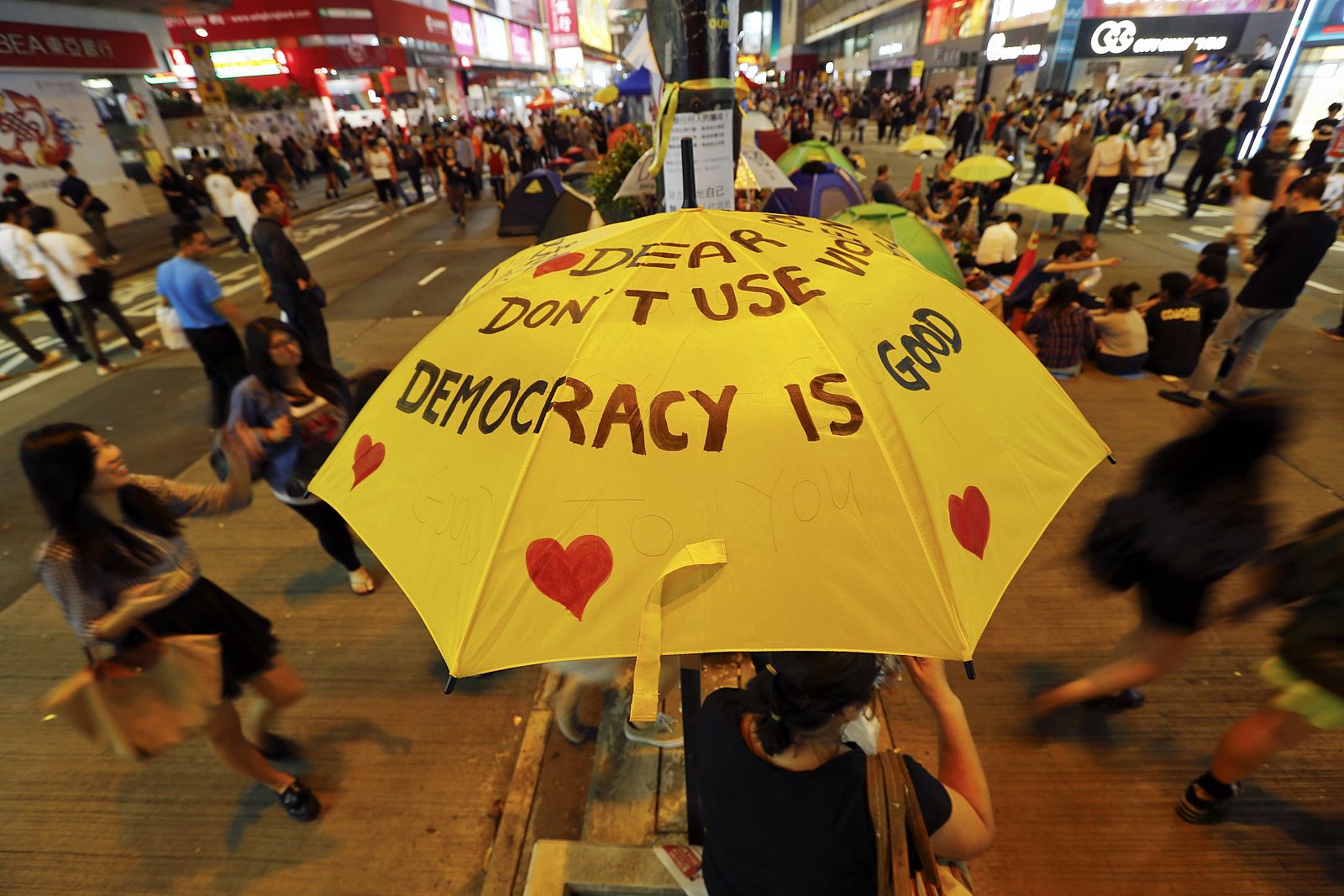Una mujer sujeta un paraguas amarillo decorado con lemas a favor de la protesta en favor de la democracia de Hong Kong.