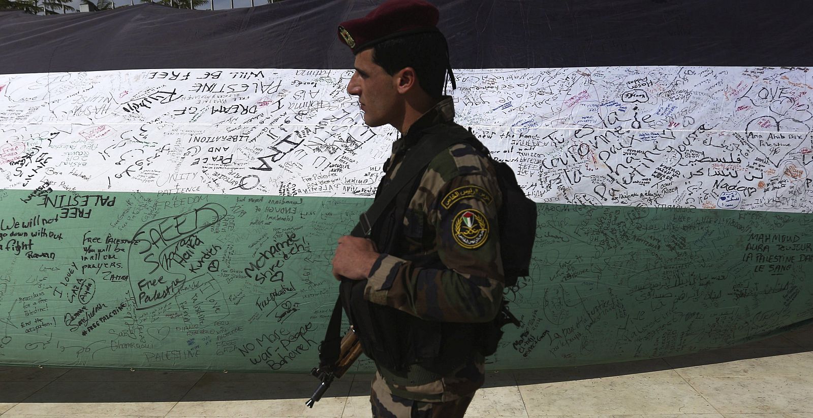 Un miembro de las Fuerzas de Seguridad palestinas pasa junto a una bandera palestina de 66 metros de largo en Ramalah