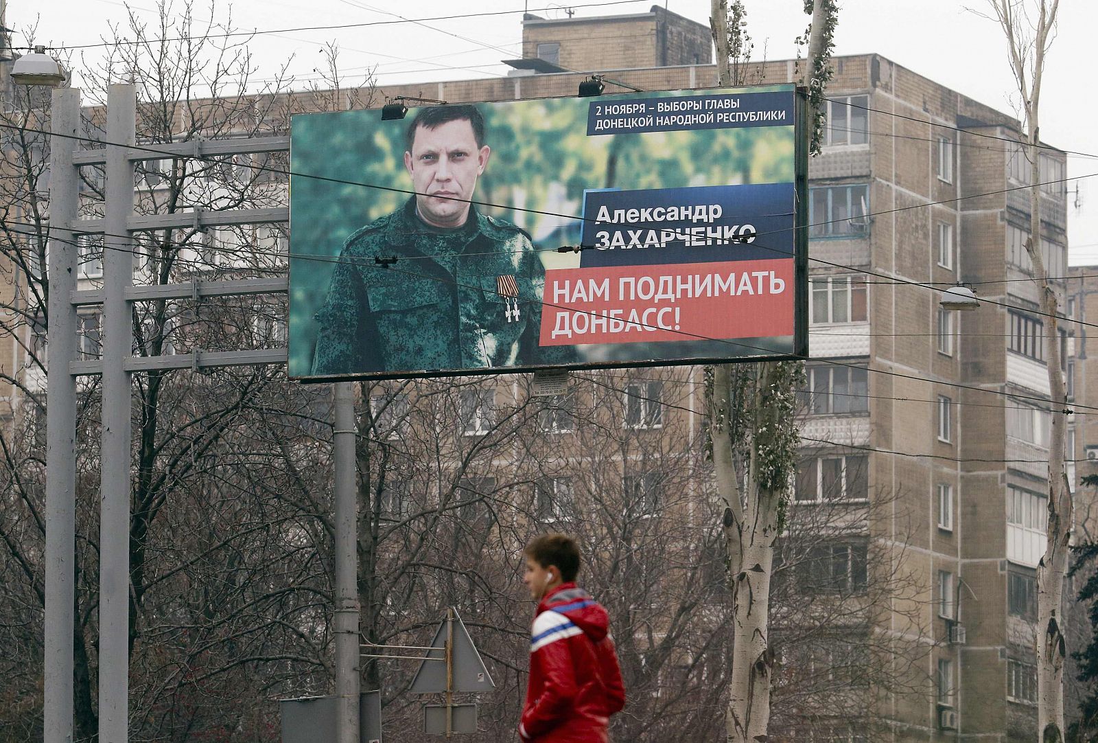 Man walks past an election information board with portrait of Zakharchenko, separatist leader of the self-proclaimed Donetsk People's Republic, in Donetsk