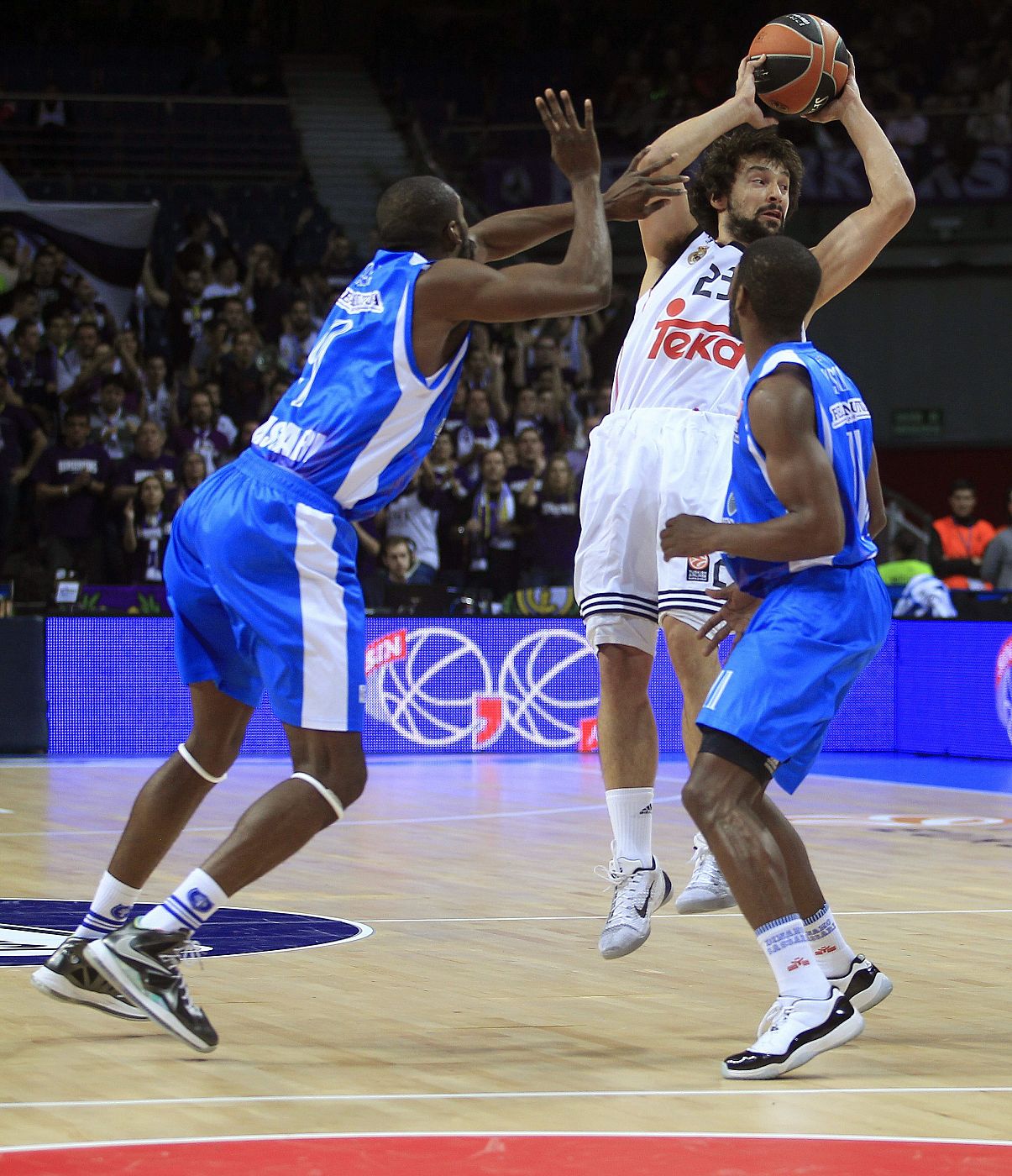 El base del Real Madrid Sergio Llull (c) ante el pívot nigeriano Shane Lawal (i) y el base estadounidense Jerome Dyson (d),