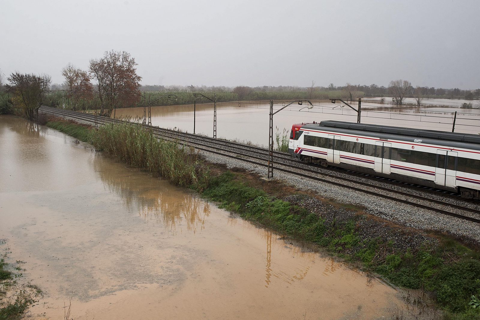 La vía del tren a la salida de Figueres en dirección a la frontera francesa rodeada de campos inundados