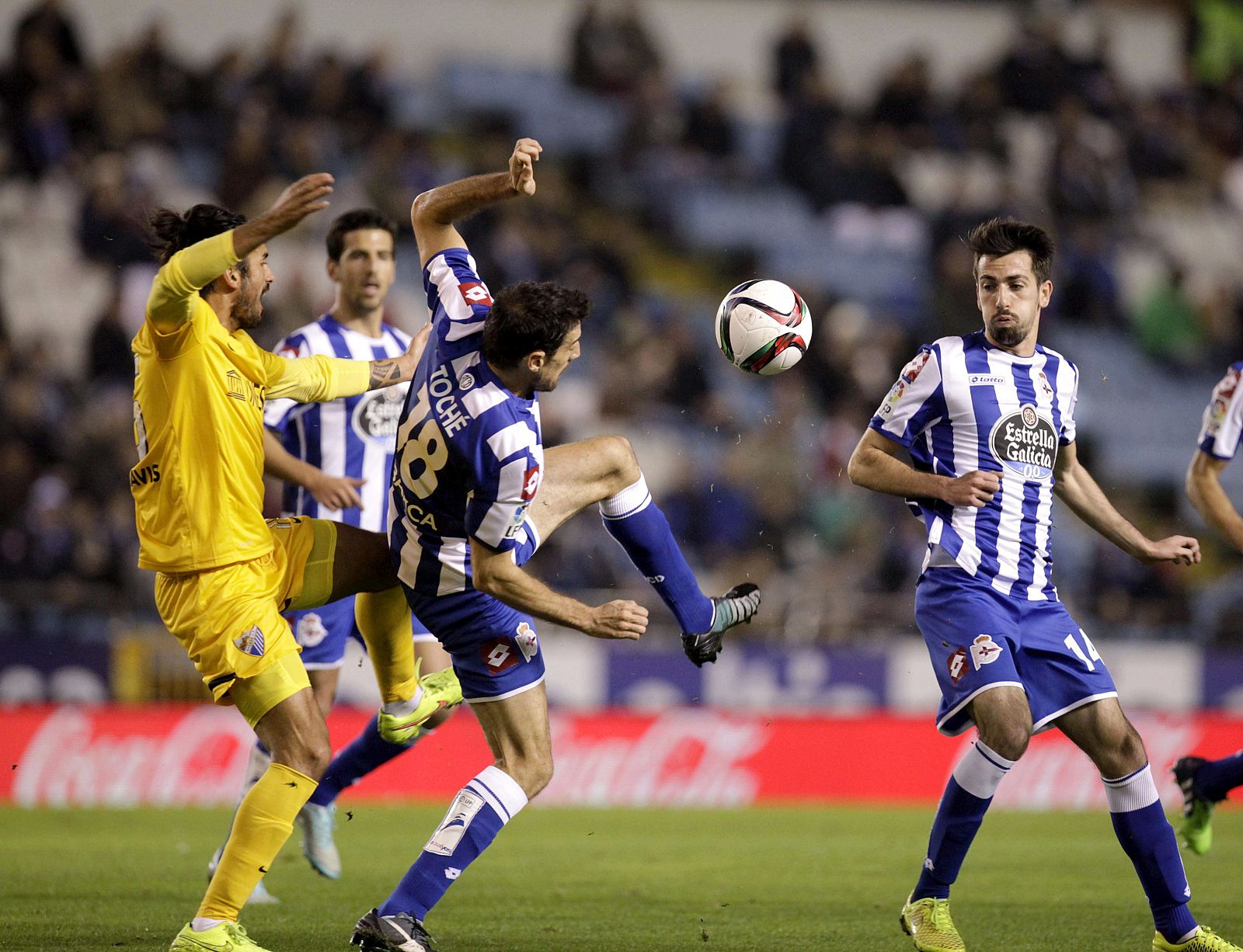 El defensa argentino del Málaga Marcos Angeleri (i) lucha un balón con los jugadores del Deportivo Isaac Cuenca (d) y Toché (c)