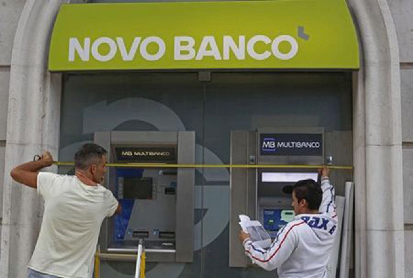 Dos trabajadores instalan el nuevo logo del Novo Banco en una oficina de Lisboa