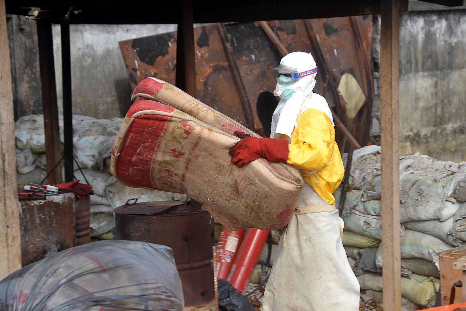 Un trabajador de salud de Guinea se deshace de un colchón en un centro de tratamiento contra el ébola en Donka