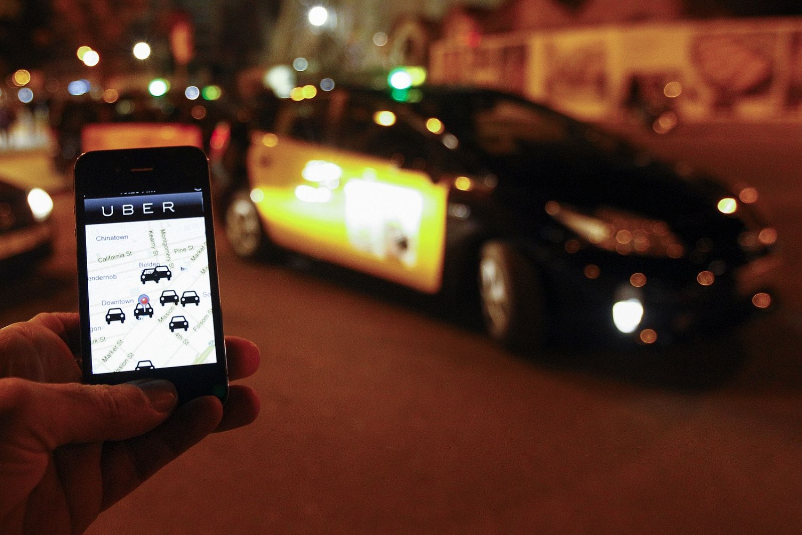 La aplicación de Uber abierta en un móvil junto a una parada de taxistas en Barcelona