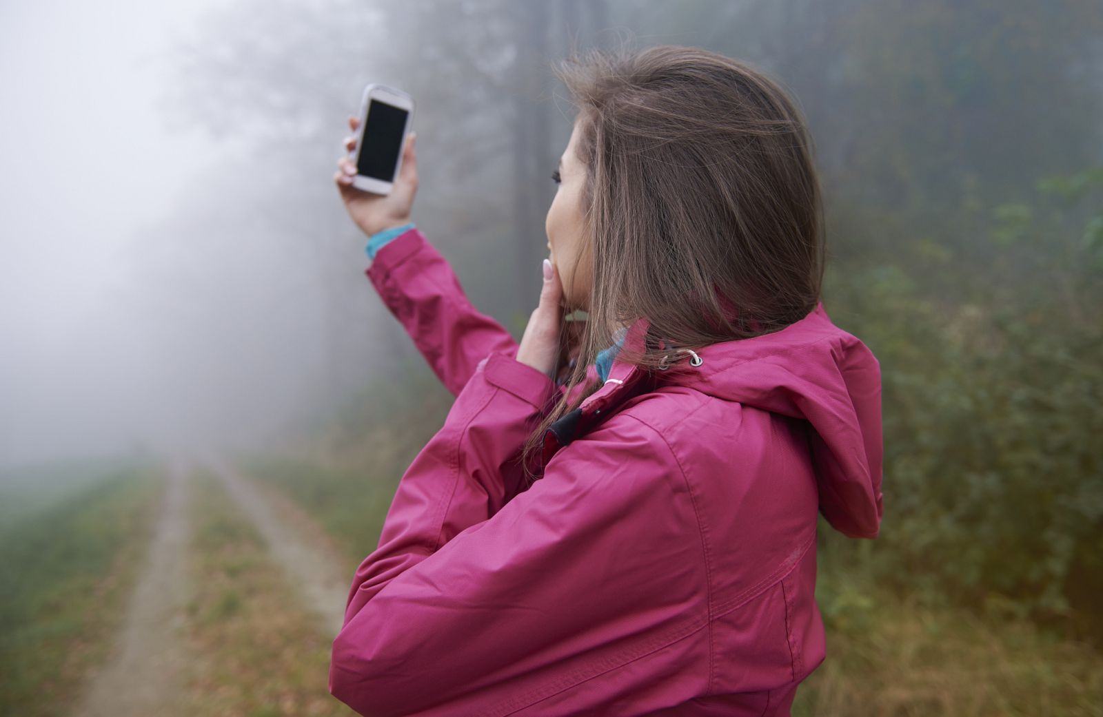 Una mujer busca cobertura con su móvil en un bosque.