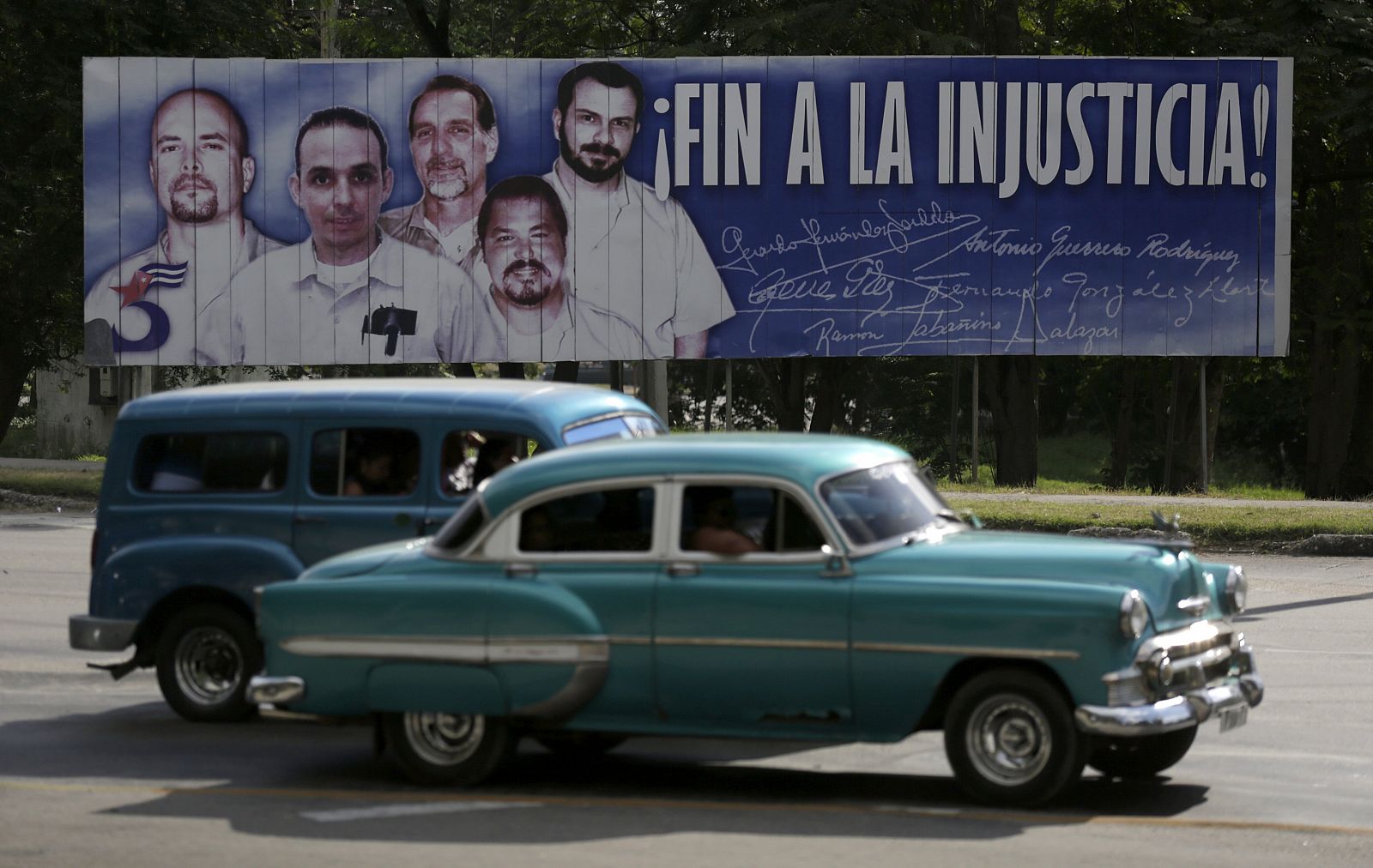 Unos coches pasan por delante de un cartel con la imgan de los cinco prisioneros cubanos de la red "La Avispa", encarcelados en EE.UU. por espionaje.