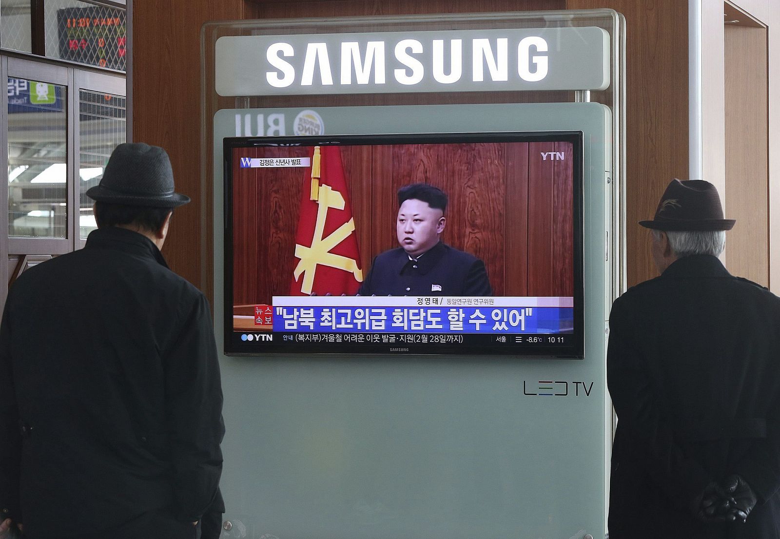 Dos surcoreanos escuchan en Seúl el mensaje de Kim Jong-un.