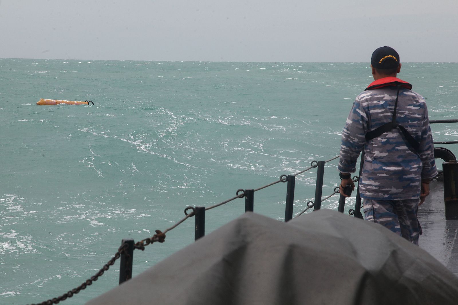 Un miembro de la Marina indonesia mira al mar en el lugar donde se encuentran los supuestros restos del vuelo siniestrado de AirAsia.