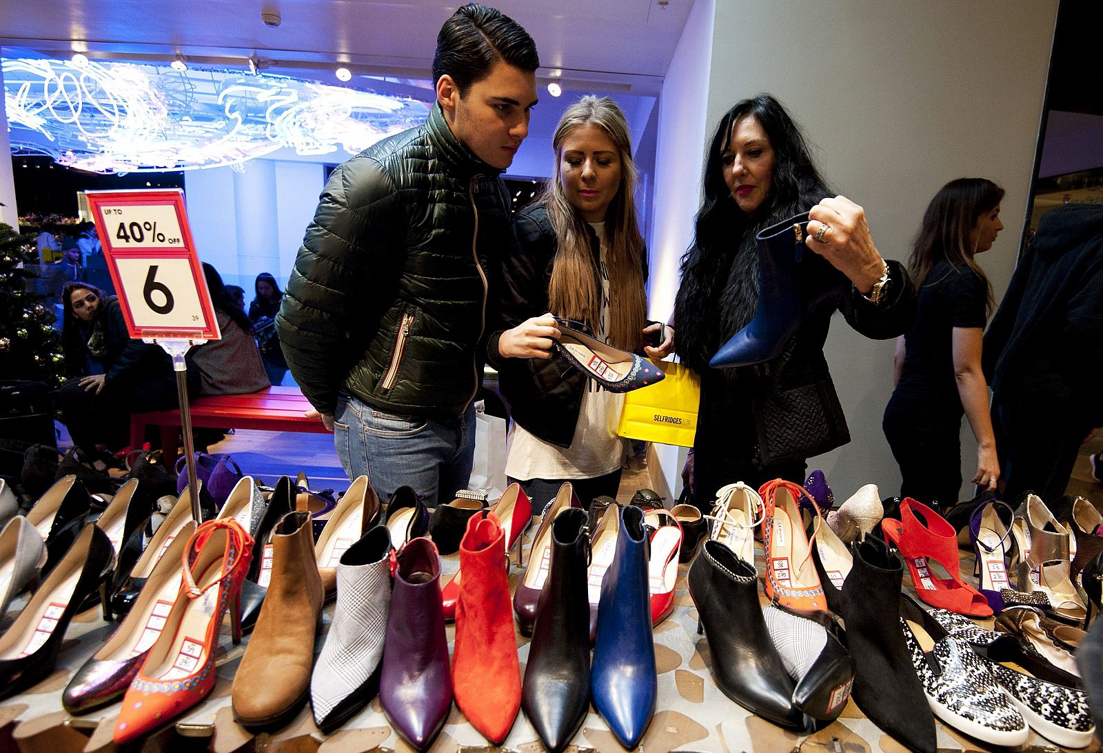 Compradores valoran los descuentos en la sección de calzado de una tienda