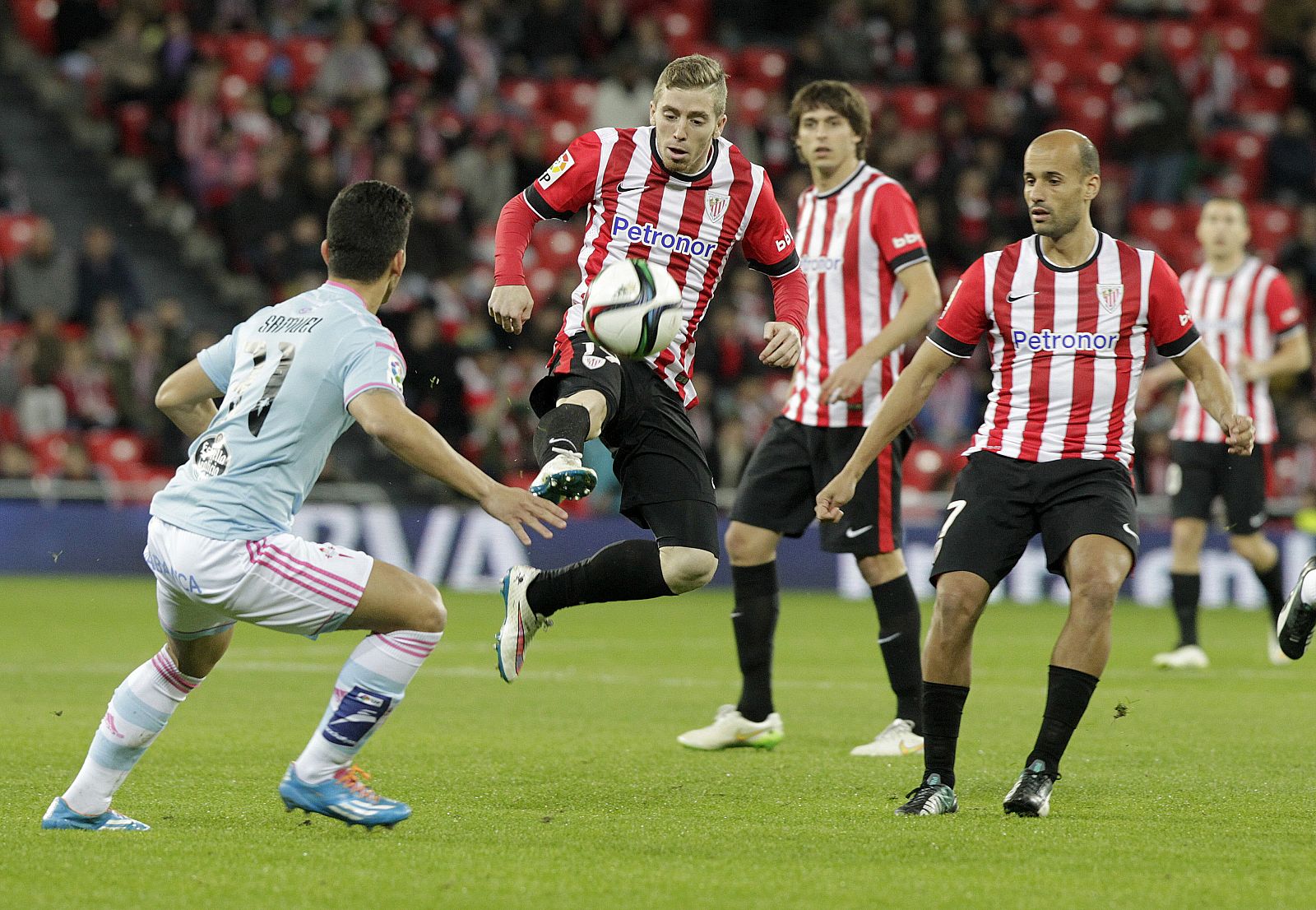 Iker Muniain (c) intenta controlar el balón ante la mirada del defensa del Celta de Vigo Samuel (i).