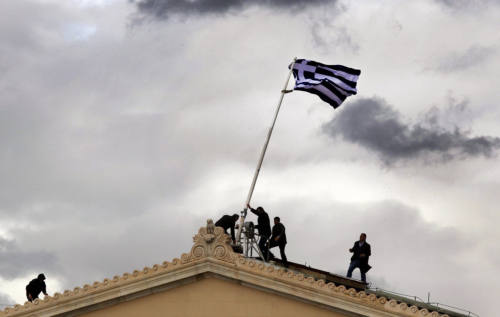 Unos operarios reemplazan la bandera de Grecia que ondea en el Parlamento griego