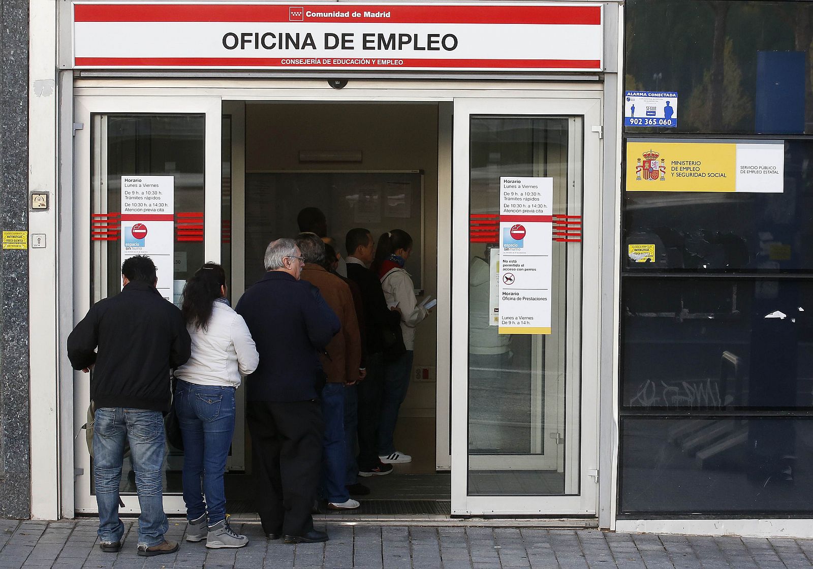 Varias personas hacen cola a la entrada de una oficina de empleo en Madrid