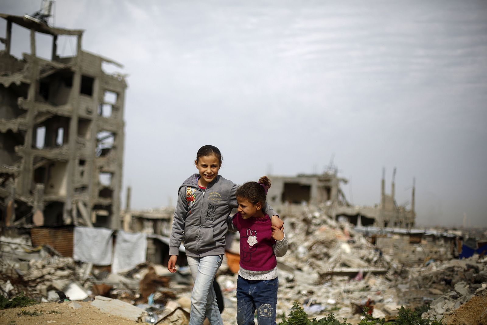 Dos niñas palestinas caminan entre edificios destruidos en un vecindario de la franja de Gaza.