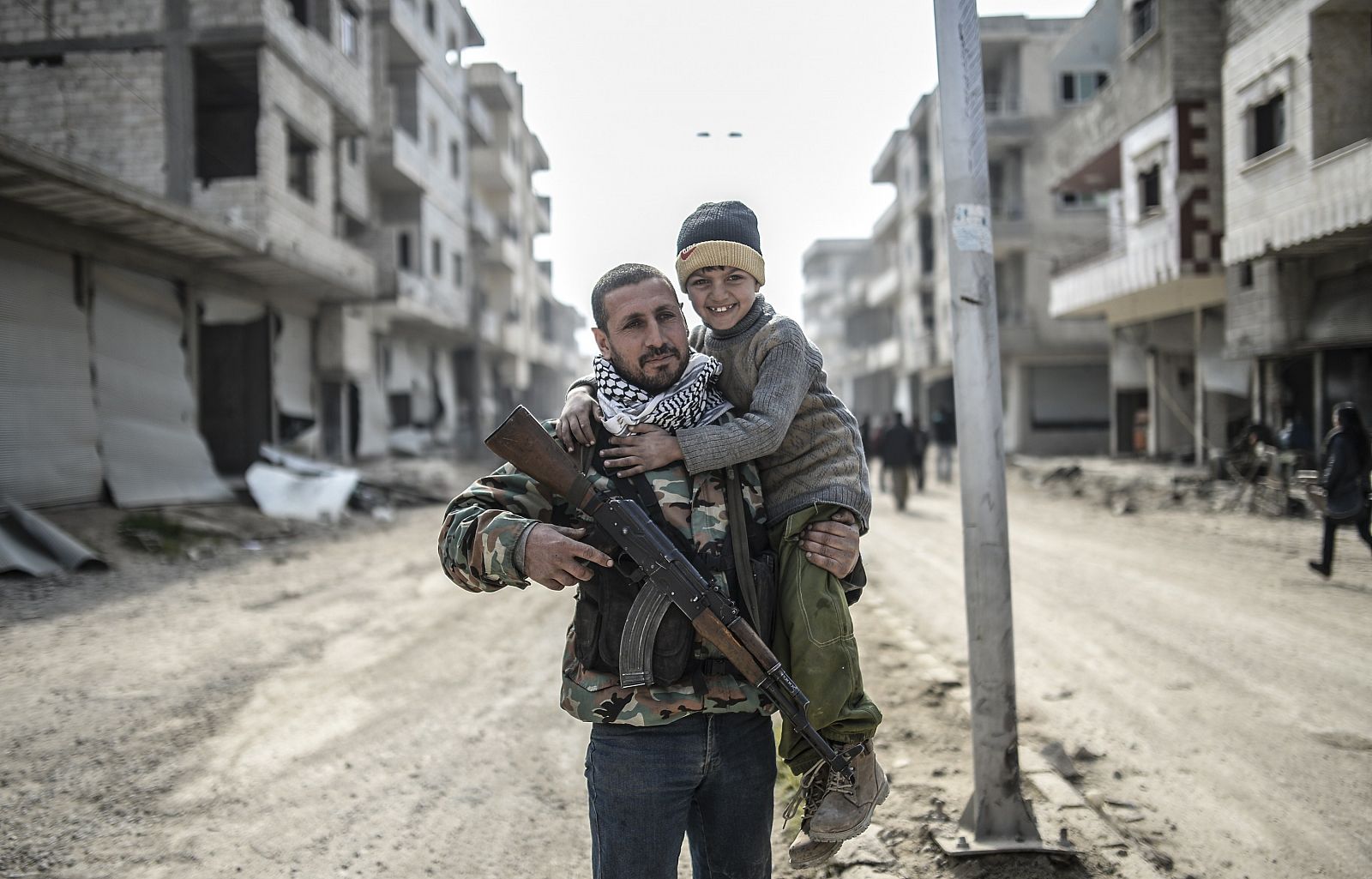 Un combatiente kurdo sostiene a su hijo en Kobani, una ciudad devastada tras cuatro meses de combates.