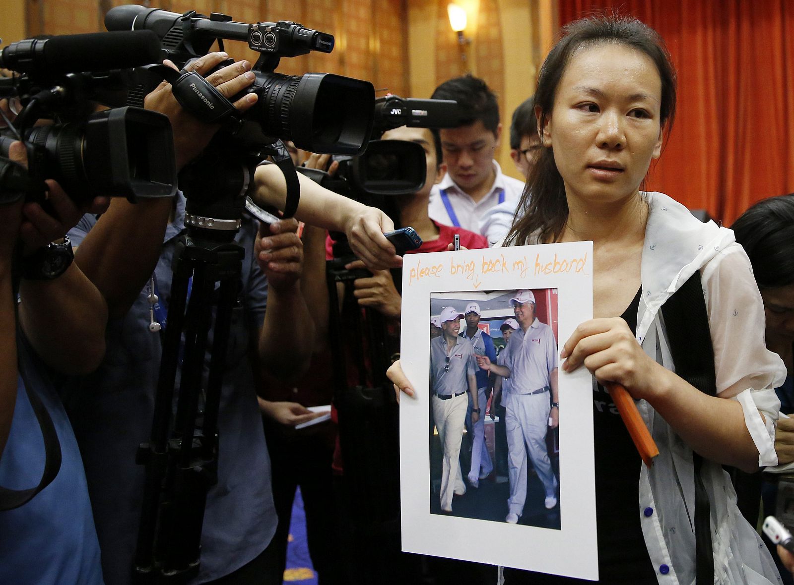La esposa de uno de los pasajeros del vuelo MH370 muestra la foto de su marido durante la conferencia de prensa en Kuala Lumpur, Malasia