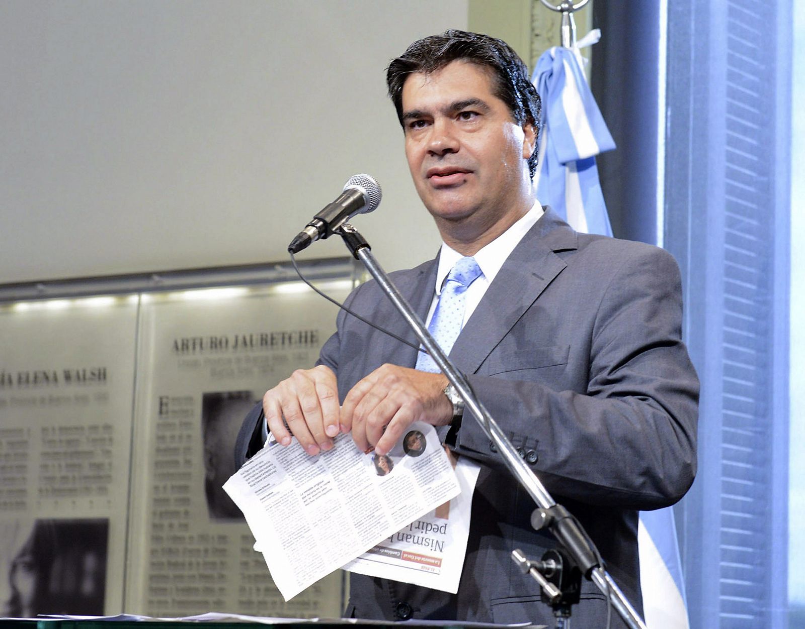 El jefe del Gabinete argentino, Jorge Capitanich, hace trizas dos páginas del diario 'Clarín' en una rueda de prensa.
