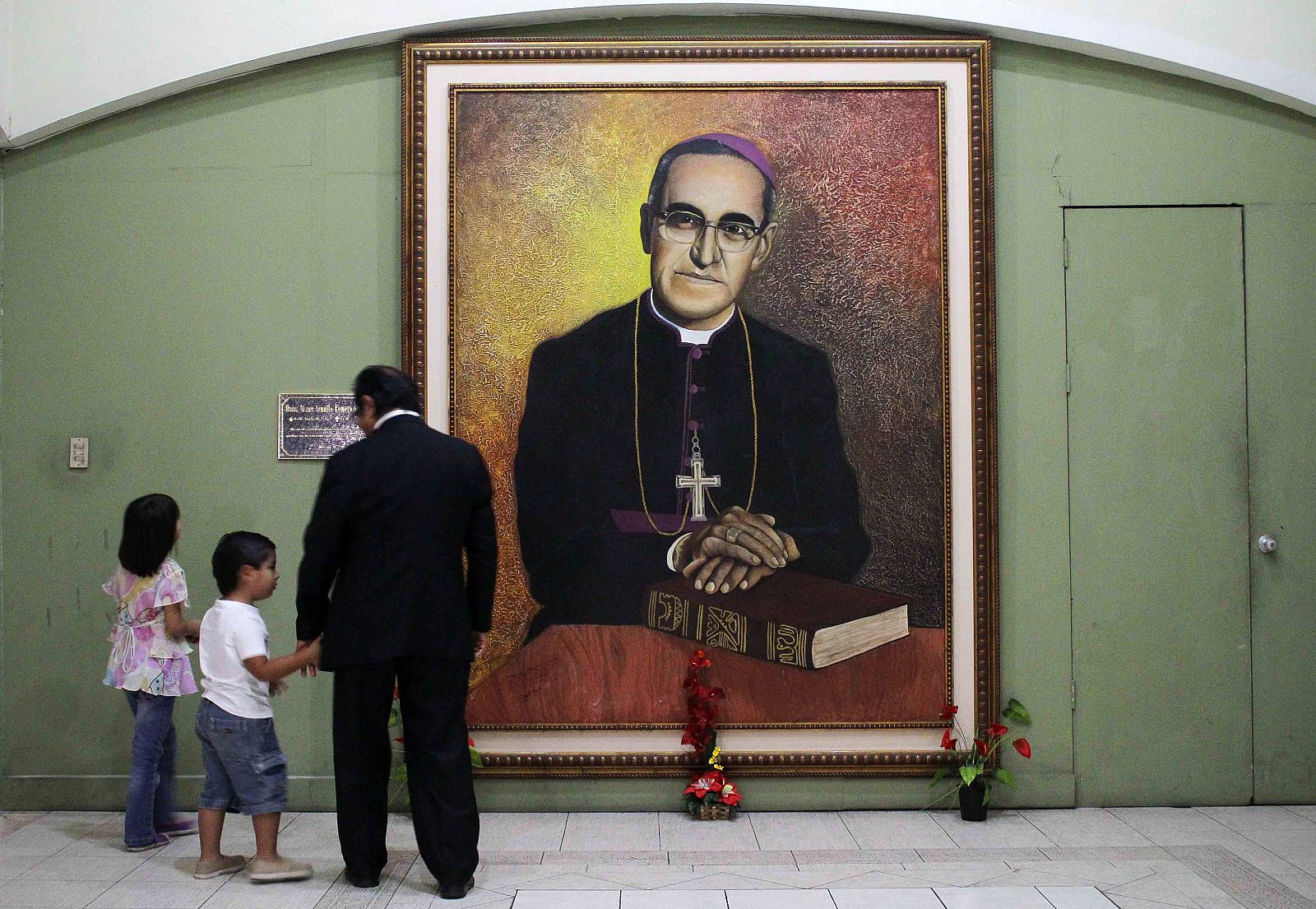 Un padre y su hija observan un retrato de Monseñor Oscar Arnulfo Romero, arzobispo de San Salvador, en la catedral de San Salvador.