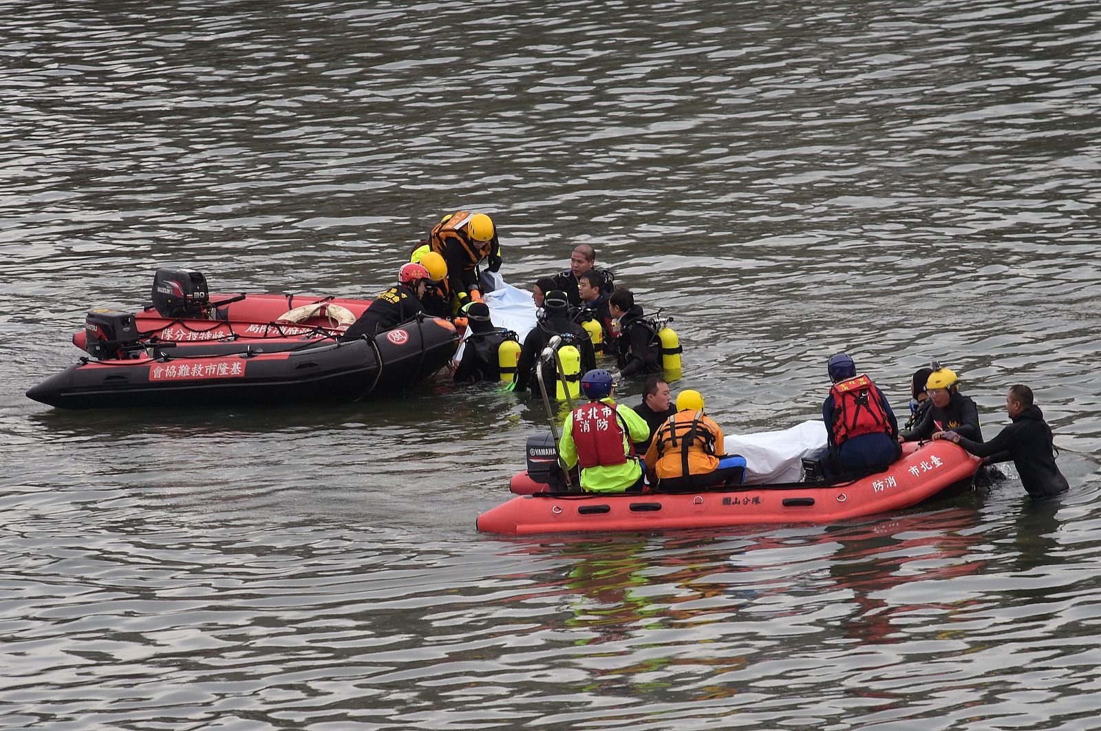 Miembros de los equipos de rescate recuperan el cuerpo de una de las víctimas del accidente de avión en el río Jilong en Taiwan
