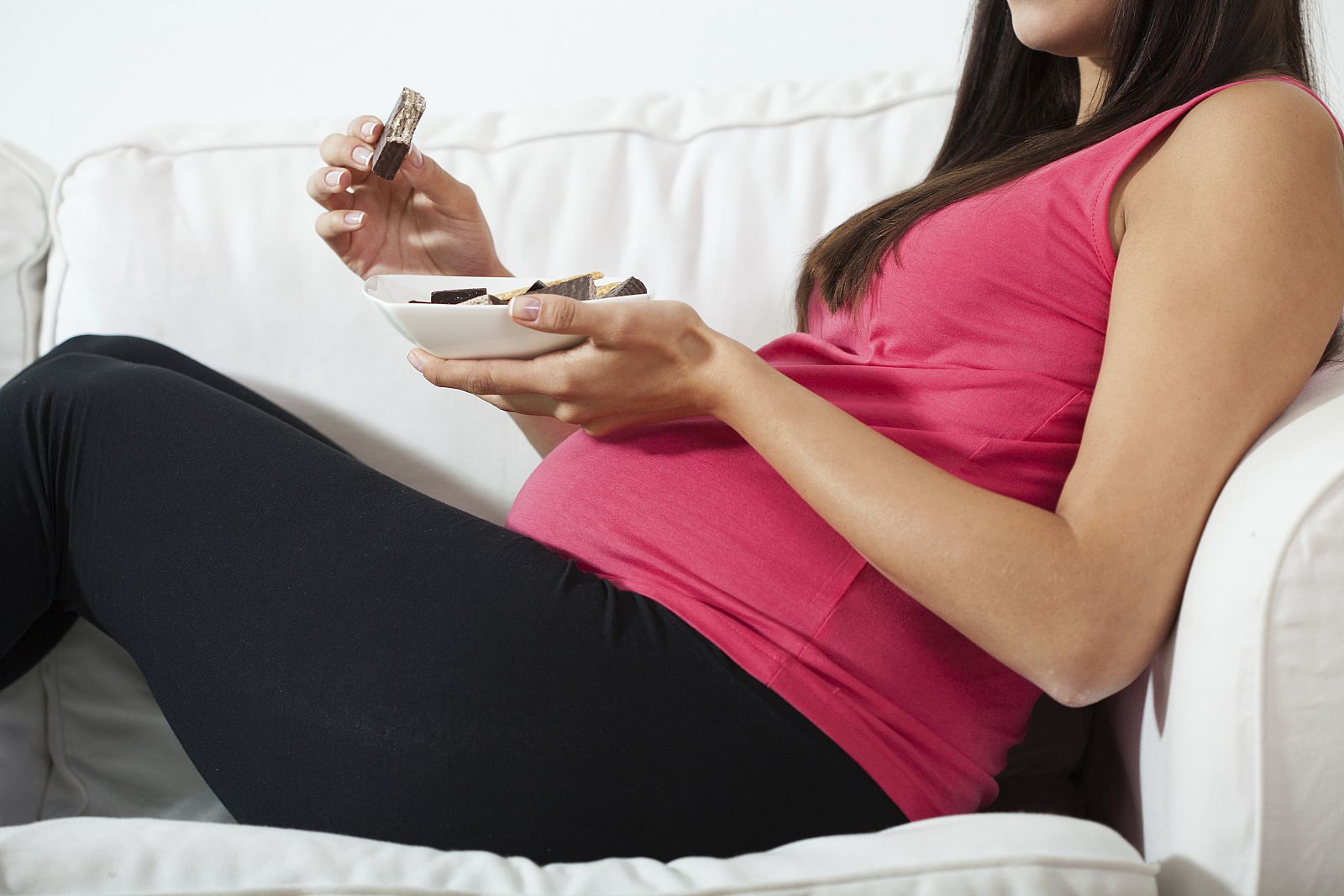 Mujer embarazada comiendo chocolate.
