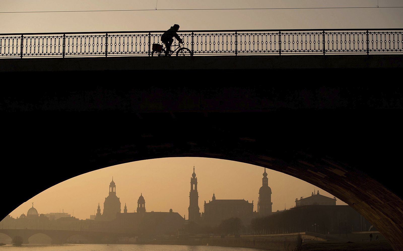 Un ciclista cruza el puente Marien al amanecer en Dresde